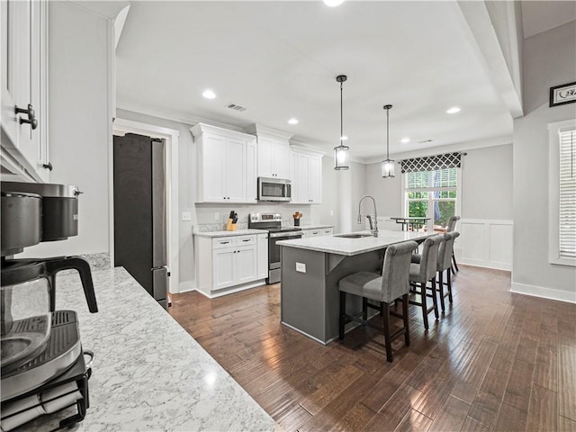 224 Blackthorn Rd, Colbert, GA 30628 - kitchen with appliances with stainless steel finishes, a breakfast bar, white cabinets, dark wood-type flooring, and a center island with sink