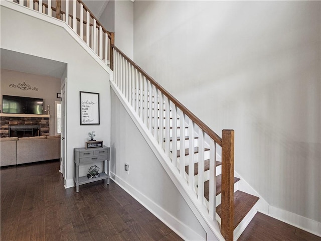 224 Blackthorn Rd, Colbert, GA 30628 - staircase featuring wood finished floors, a stone fireplace, and a towering ceiling