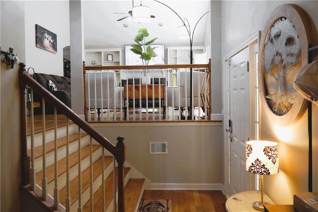 stairs with wood-type flooring and ceiling fan