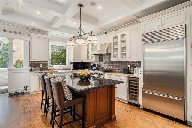 1634 Lenox Rd NE, Atlanta, GA 30306 - kitchen with white cabinets, stainless steel appliances, wine cooler, light wood-style floors, and wall chimney exhaust hood