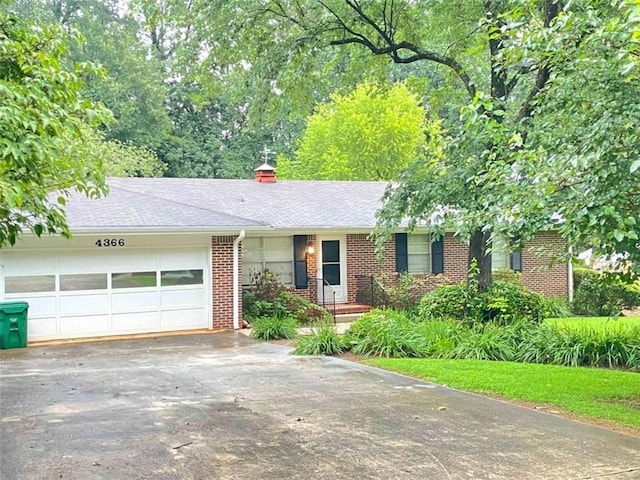 single story home featuring a garage, brick siding, driveway, and roof with shingles