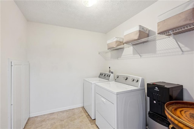 washroom featuring laundry area, separate washer and dryer, baseboards, and a textured ceiling
