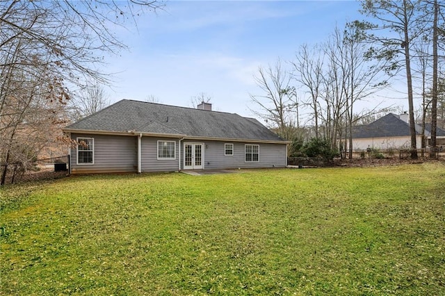 rear view of property featuring french doors, a yard, a chimney, and fence