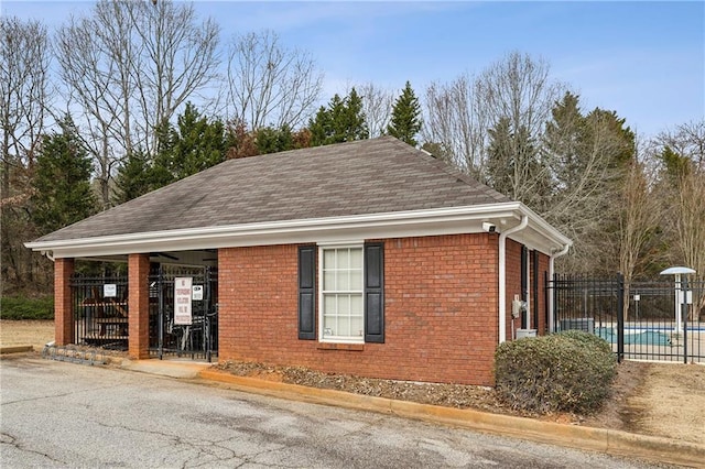 view of property exterior with brick siding, a community pool, and fence