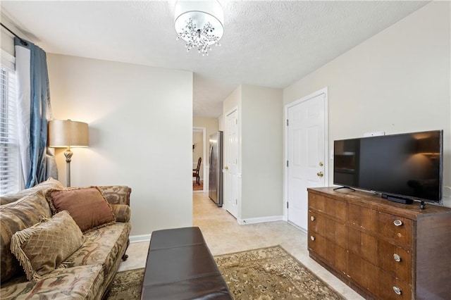 living room featuring light carpet, baseboards, a chandelier, and a textured ceiling
