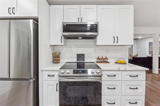 kitchen featuring white cabinetry, wood finished floors, light stone countertops, and stainless steel appliances