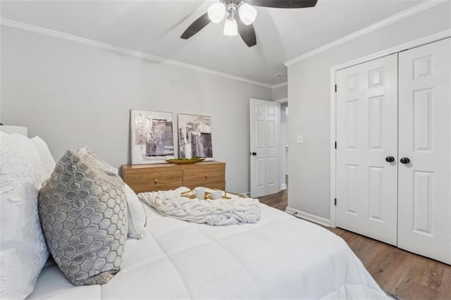 bedroom with wood finished floors, baseboards, ceiling fan, ornamental molding, and a closet