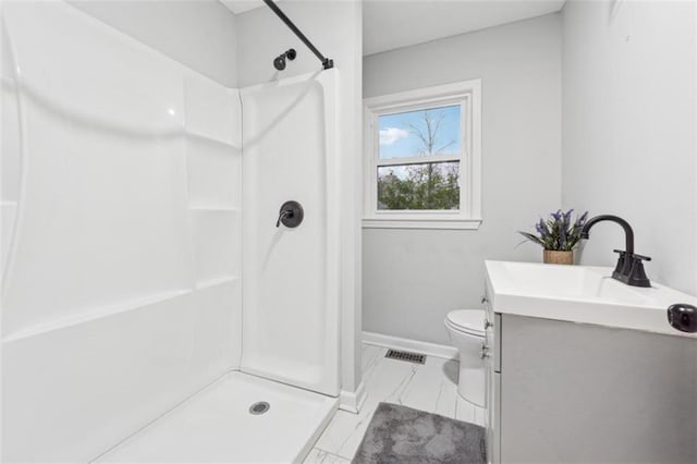 bathroom with toilet, marble finish floor, a stall shower, baseboards, and vanity