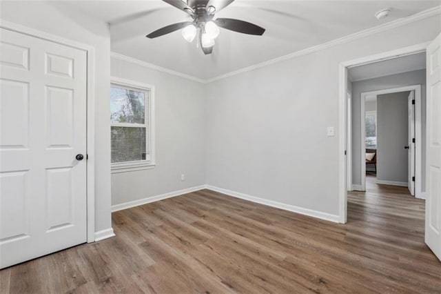 unfurnished room featuring wood finished floors, a ceiling fan, baseboards, and ornamental molding