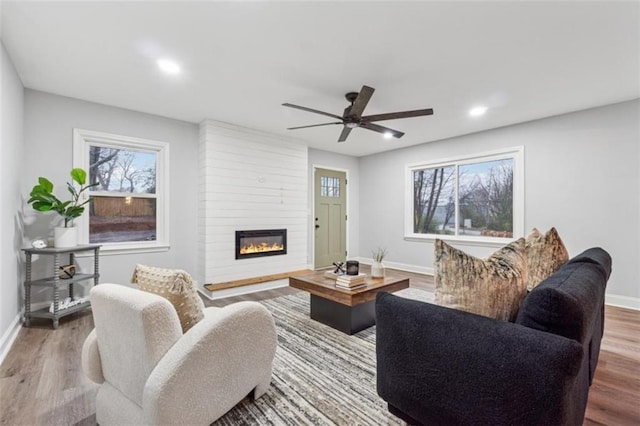 living room with a healthy amount of sunlight, a ceiling fan, baseboards, and wood finished floors