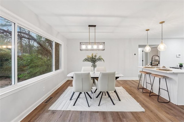 dining space featuring visible vents, baseboards, a healthy amount of sunlight, and wood finished floors