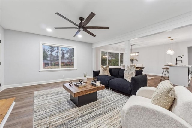 living room featuring recessed lighting, baseboards, wood finished floors, and ceiling fan with notable chandelier