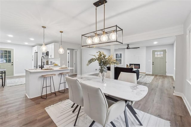 dining area with wood finished floors, recessed lighting, a fireplace, and baseboards