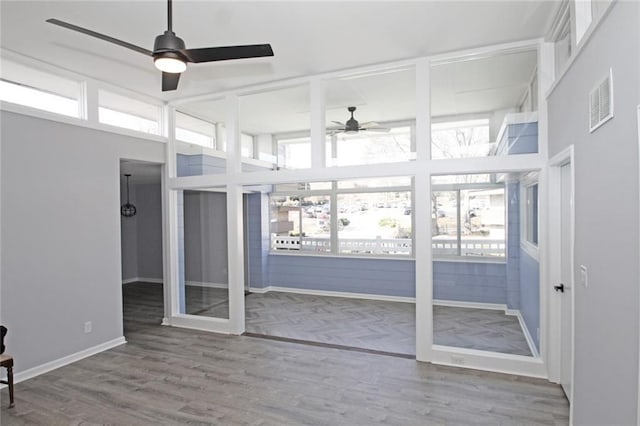 unfurnished sunroom with a ceiling fan, a healthy amount of sunlight, and visible vents