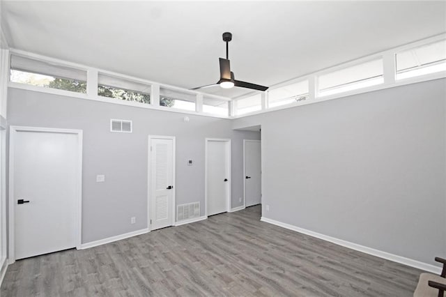 unfurnished room featuring a ceiling fan, wood finished floors, visible vents, and baseboards