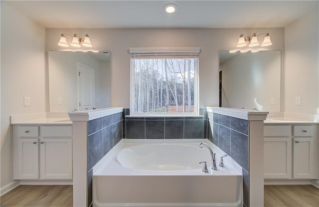 full bath with wood finished floors, a bath, and vanity