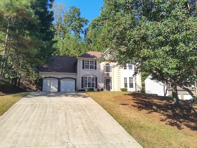 colonial house with a front lawn, concrete driveway, and an attached garage