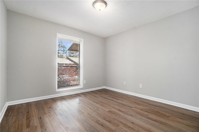 spare room featuring wood finished floors and baseboards