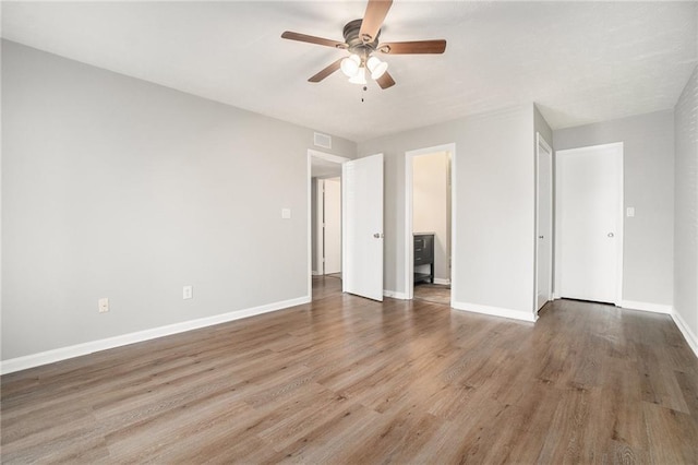 unfurnished bedroom with visible vents, ceiling fan, baseboards, wood finished floors, and ensuite bath