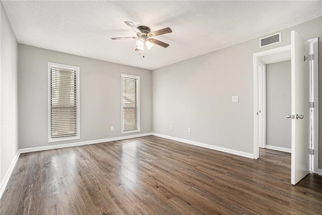empty room with baseboards, visible vents, wood finished floors, and a ceiling fan