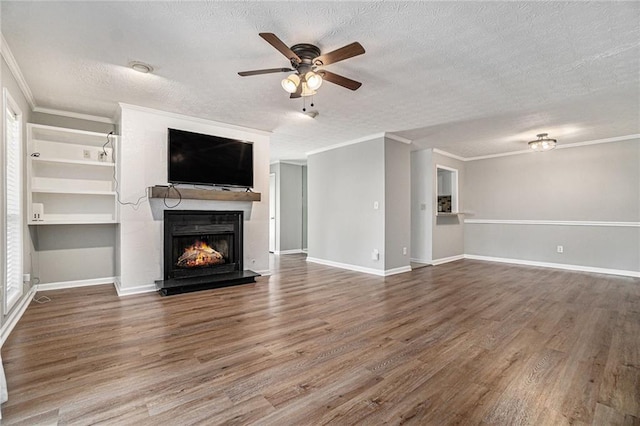 unfurnished living room with a textured ceiling, wood finished floors, a ceiling fan, and a warm lit fireplace