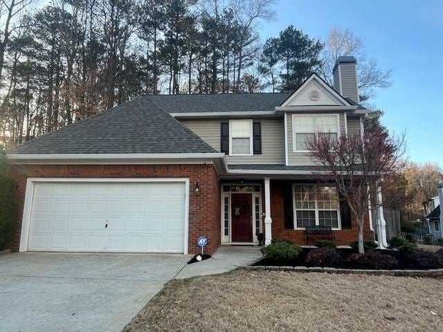 traditional home with driveway, a shingled roof, a garage, brick siding, and a chimney