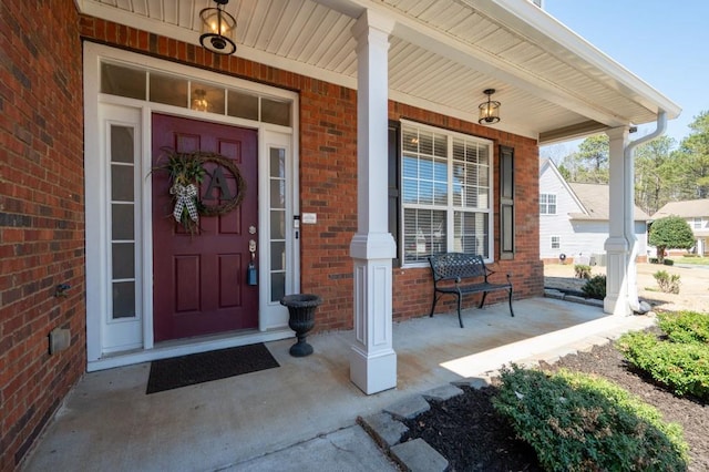 doorway to property featuring brick siding and a porch