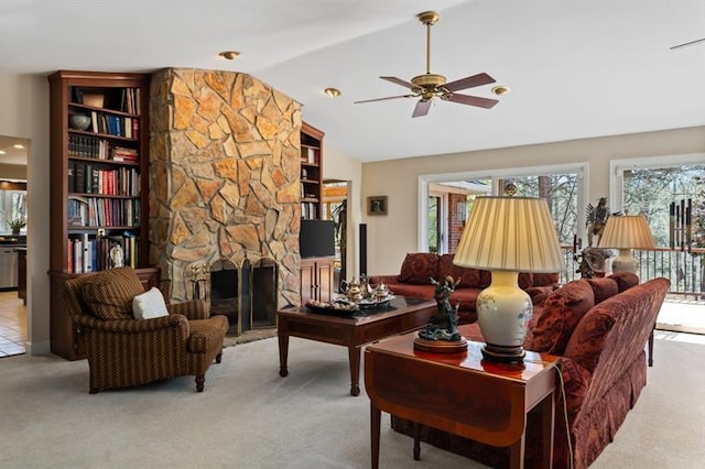 carpeted living room with a stone fireplace, ceiling fan, and lofted ceiling