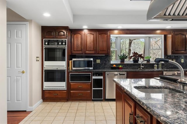 kitchen with sink, stainless steel appliances, dark stone countertops, and tasteful backsplash