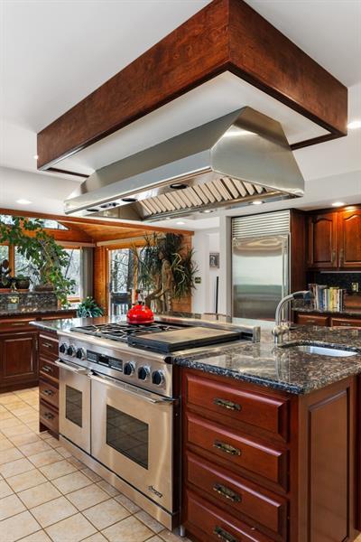 kitchen featuring extractor fan, high end appliances, light tile patterned floors, sink, and beam ceiling