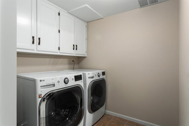 washroom featuring dark tile patterned flooring, cabinets, and washing machine and dryer