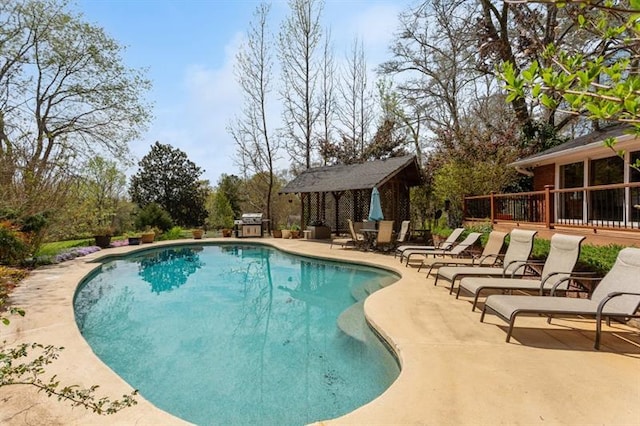 view of swimming pool featuring a patio area, an outdoor structure, and a wooden deck