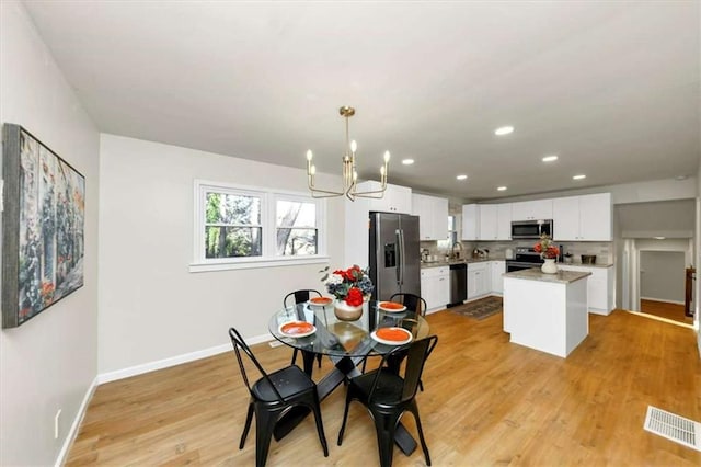 dining space with sink, a chandelier, and light hardwood / wood-style floors