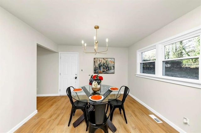 dining area with light hardwood / wood-style flooring and an inviting chandelier