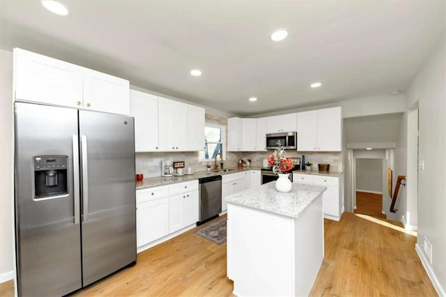 kitchen featuring backsplash, white cabinetry, a kitchen island, and stainless steel appliances