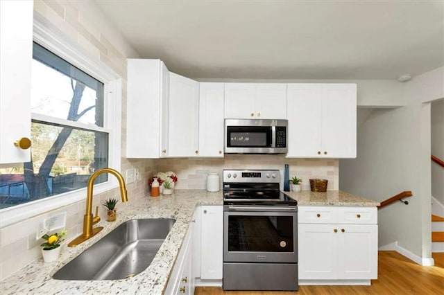 kitchen featuring light stone counters, white cabinetry, sink, and appliances with stainless steel finishes