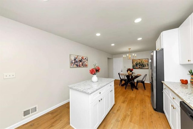 kitchen with light stone countertops, stainless steel appliances, decorative light fixtures, white cabinets, and a kitchen island