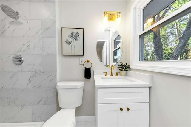 bathroom featuring toilet, vanity, and tiled shower