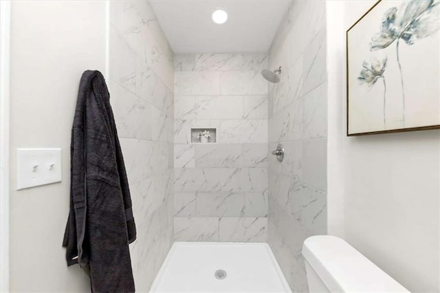 bathroom featuring tiled shower and toilet