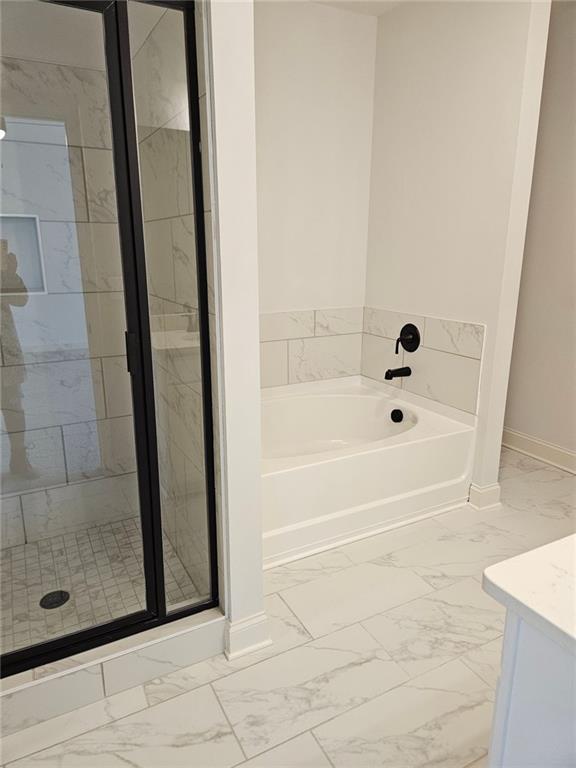 228 Trellis Walk, Macon, GA 31220 - bathroom featuring marble look tile flooring, a bath, baseboards, and a shower stall