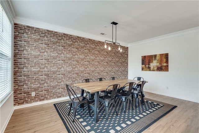 dining area with crown molding, brick wall, light wood-type flooring, and a wealth of natural light