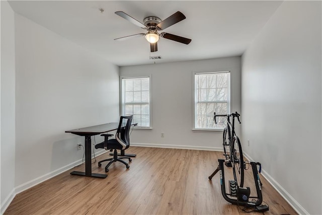 home office with light hardwood / wood-style flooring and ceiling fan