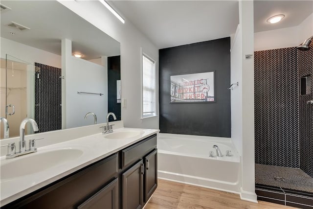 bathroom featuring hardwood / wood-style flooring, vanity, and plus walk in shower