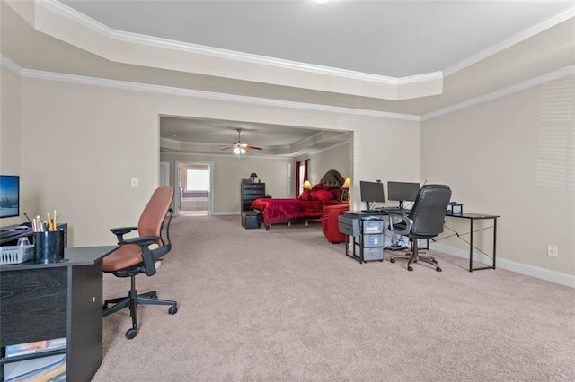 carpeted office with ceiling fan, crown molding, and a tray ceiling