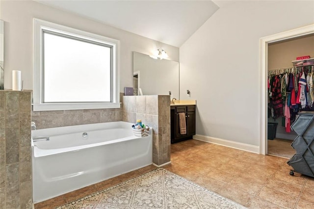 bathroom with a tub to relax in, vanity, and vaulted ceiling