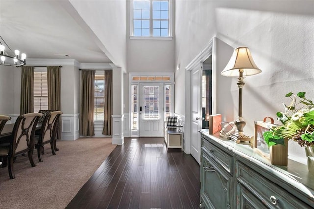 foyer entrance with dark hardwood / wood-style floors, ornamental molding, and a notable chandelier