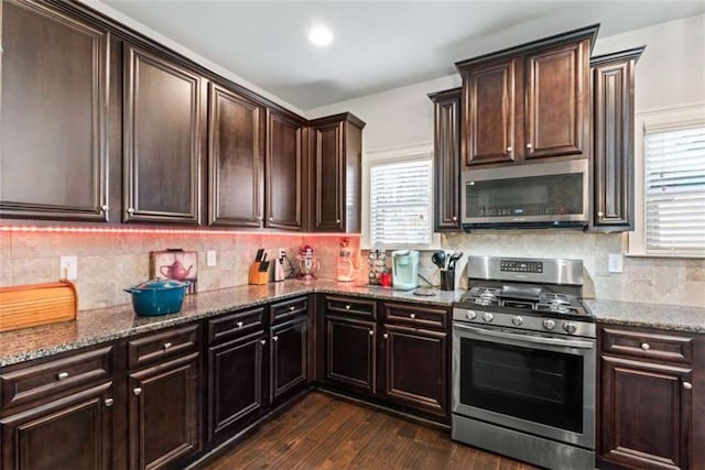 kitchen featuring a healthy amount of sunlight, appliances with stainless steel finishes, dark hardwood / wood-style flooring, and stone counters