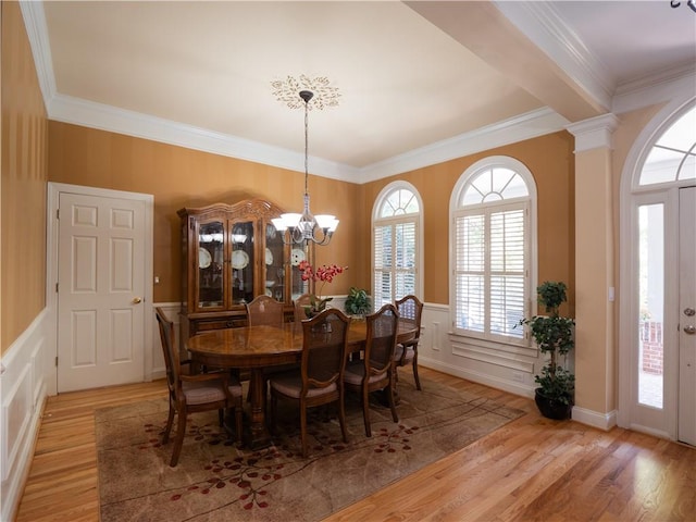 dining room with decorative columns, light hardwood / wood-style flooring, a chandelier, and ornamental molding