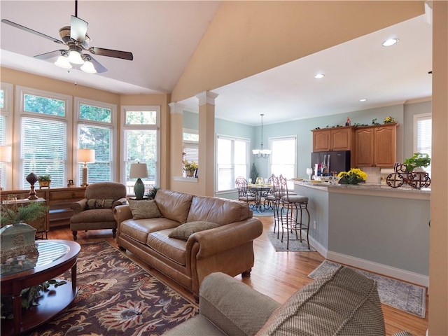 living room with light hardwood / wood-style floors, a healthy amount of sunlight, and ceiling fan with notable chandelier