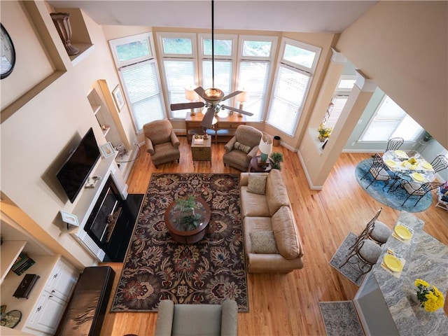 living room featuring a towering ceiling, hardwood / wood-style flooring, and ceiling fan